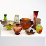 Mehrere farbige Jugendstil Kunstglas Vasen und Schalen auf weißem Sockel vor neutralem Hintergrund – Cameoglas und dekorative Glasobjekte im Stil von Gallé, Daum Nancy, Lötz Wien und Lalique